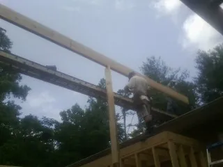 Carpenter setting a ridge beam over a new addition frame — Ice Dam Removal by Roofing Brothers in Earlville