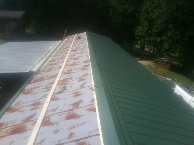 Old rusted panels beside newly installed green metal roofing — Wind Damage Roof Repair by Roofing Brothers in Earlville