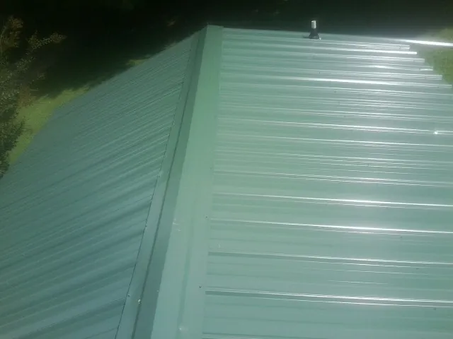 New green metal panels meeting at the ridge of a roof — Flat Roof Repair work by our crew in Earlville