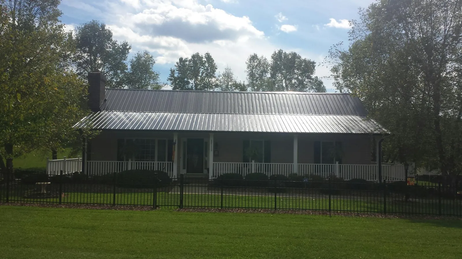 Gray metal roof on a brick ranch with a full width front porch — Gutter Guard Installation work by our crew in Earlville